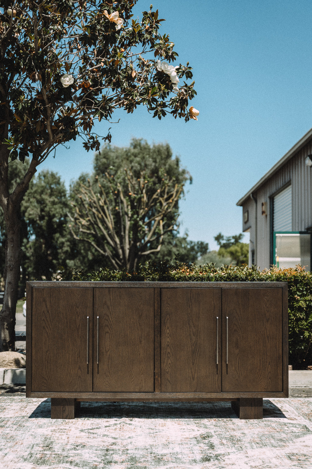 Wooden outdoor cabinet with metal handles in a garden setting