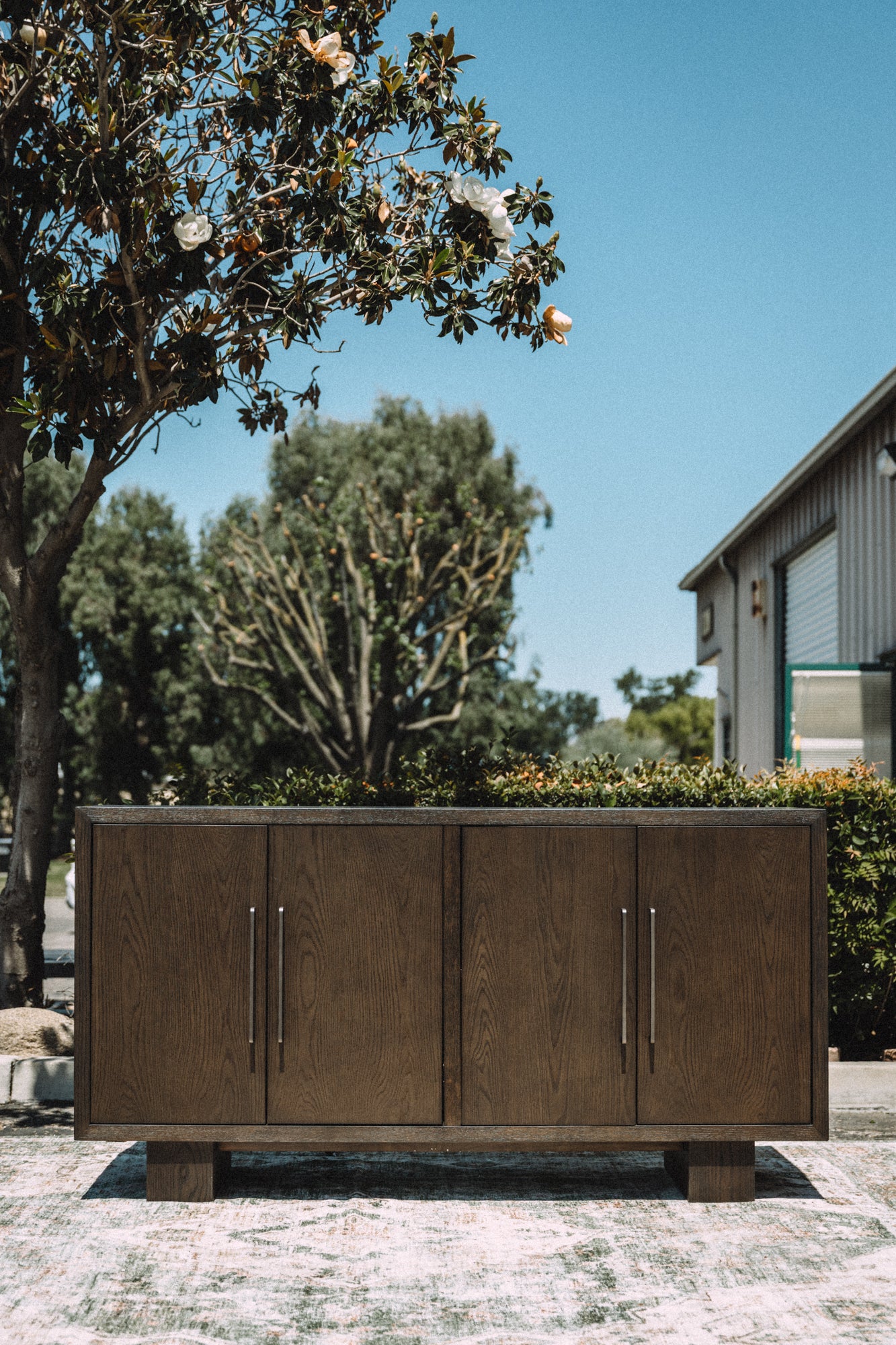 Wooden outdoor cabinet with metal handles in a garden setting